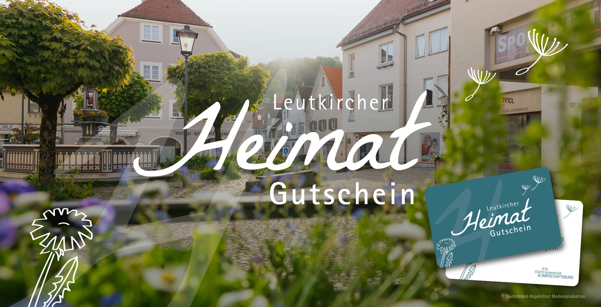 Blick auf die Innenstadt von Leutkirch im Allgäu mit Schriftzug „Leutkircher Heimat Gutschein“ und abgebildeter Gutscheinkarte im Vordergrund.